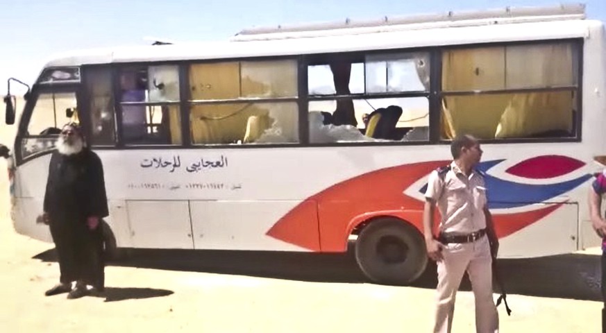 This image released by the Minya governorate media office shows a policeman and a priest next to a bus after stormed the bus in Minya, Egypt, Friday, May 26, 2017. Egyptian officials say dozens of peo ...
