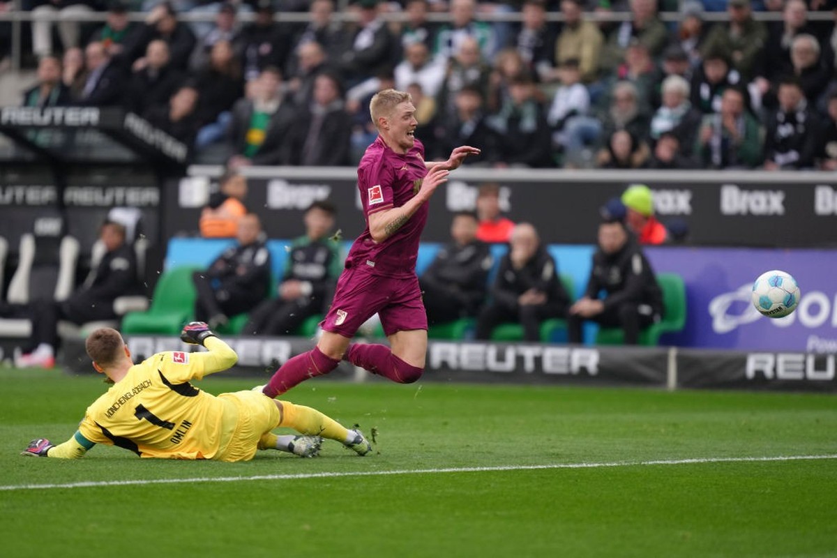MOENCHENGLADBACH, GERMANY - FEBRUARY 22: Fredrik Jensen of FC Augsburg is tackled by Jonas Omlin of Borussia Mönchengladbach during the Bundesliga match between Borussia Mönchengladbach and FC Augsbur ...
