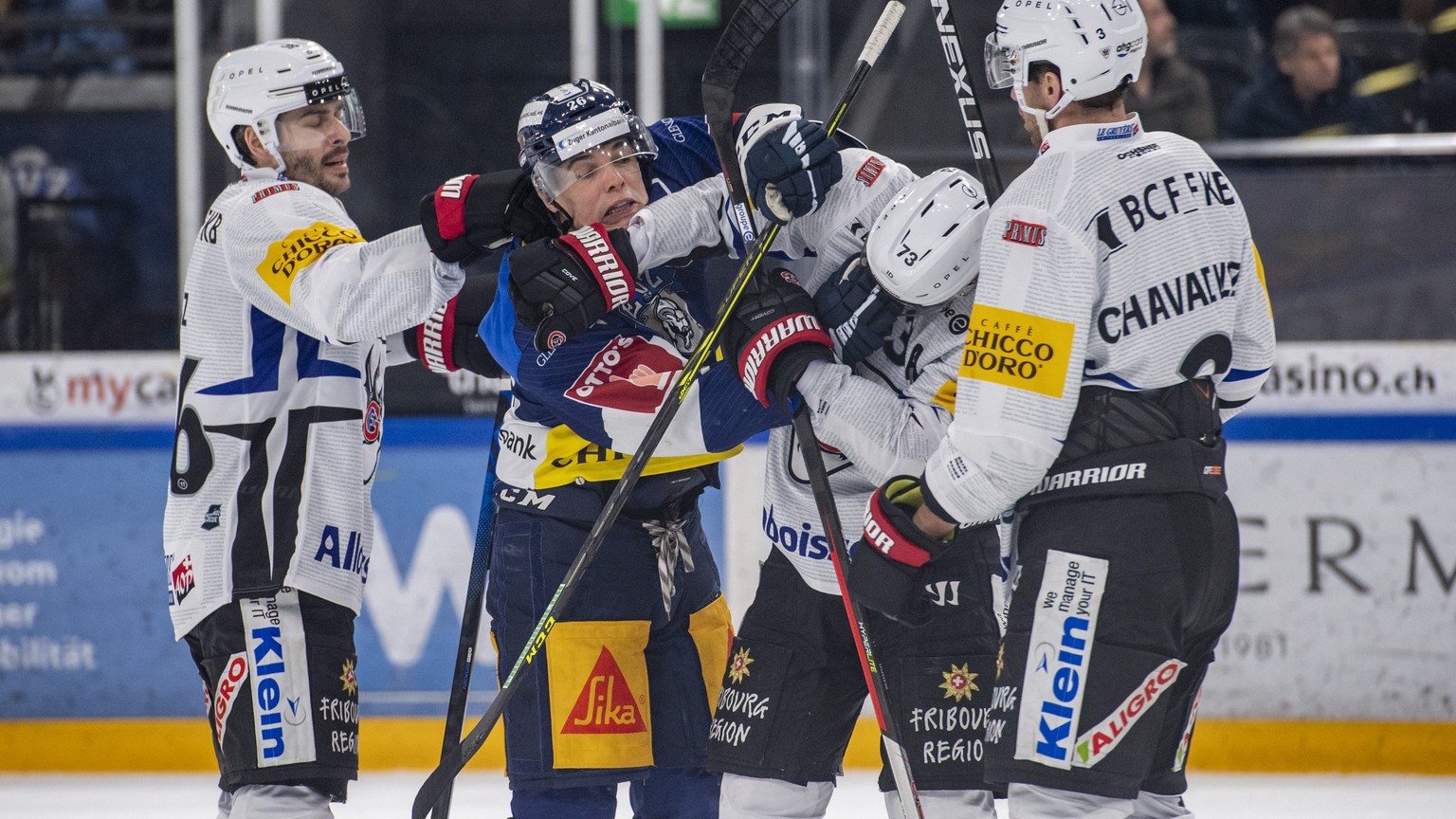 Reto Suri, mitte links, von Zug im Kanpf gegen Sandro Schmid, mitte rechts, von Fribourg beim Eishockey Qualifikationsspiel der National League zwischen dem EV Zug und dem HC Fribourg Gotteron am Mitt ...