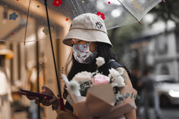 epa09413177 A woman carrying flowers walks on the street in Shanghai, China, 14 August 2021. In 2021, the Chinese Valentine?s Day, Qixi Festival, falls on 14 August on the Gregorian calendar. Accordin ...