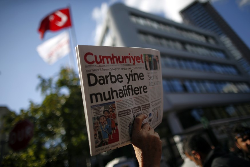 A man holds up the latest copy of Cumhuriyet outside its headquarters after Turkish police detained the chief editor and at least eight senior staff of Turkey&#039;s opposition Cumhuriyet newspaper in ...