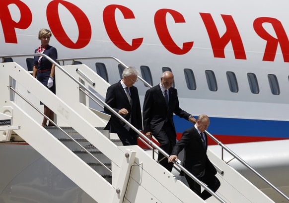 Russian President Vladimir Putin, right, is followed by Italian Head of the Diplomatic Protocol Inigo Lambertini, second from right, as he steps off the plane as he arrives at Rome's international air ...