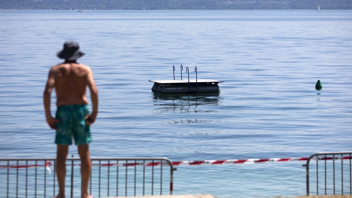 Ein Mann schaut auf den mit Absperrbaendern geschlossenen Strand bei Boudry, am Freitag, 31. Juli 2020 in Boudry am Neuenburgersee. Die Behoerden im Kanton Neuenburg haben ein Badeverbot fuer den Stra ...
