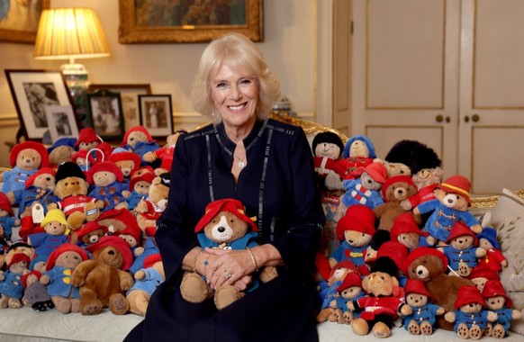 LONDON, ENGLAND - OCTOBER 13: (EDITORIAL USE ONLY Camilla, Queen Consort, poses with a collection of Paddington cuddly toys in the Morning Room at Clarence House, on the 64th anniversary of the public ...