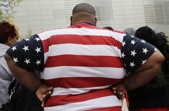 In this Thursday, May 8, 2014 photo, an overweight man wears a shirt patterned after the American flag during a visit to the World Trade Center, in New York. Rising numbers of American adults have the ...