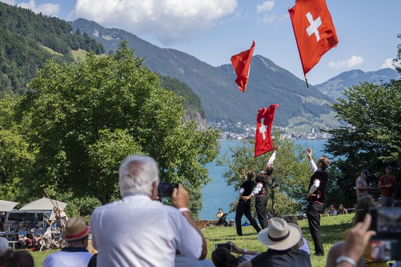 Drei Fahnenschwinger in aktion auf der Ruetliwiese waehrend der Bundesfeier auf dem Ruetli, welche im Zeichen des Schweizer Traditionssport Schwingen steht, am Montag, 1. August 2022. (KEYSTONE/Urs Fl ...