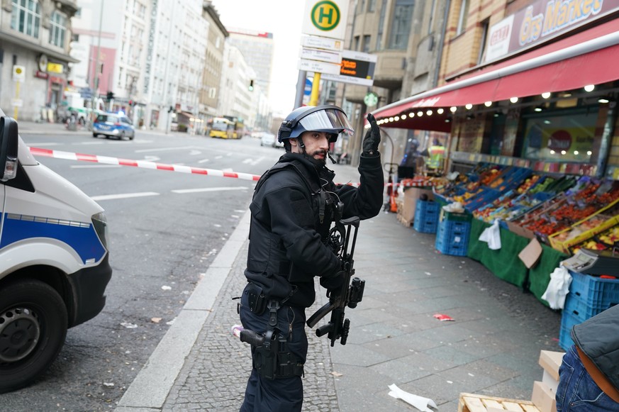 A policeman in protective gear instructs the passers-by to bring themselves to safety during a police operation near the former Checkpoint Charlie in Berlin, Germany, Monday, Dec. 30, 2019. Police say ...