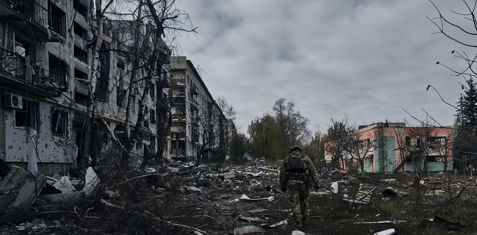 A Ukrainian soldier passes by houses ruined in the Russian shelling in Bakhmut, Donetsk region, Ukraine, Thursday, Nov. 10, 2022. (AP Photo/LIBKOS)