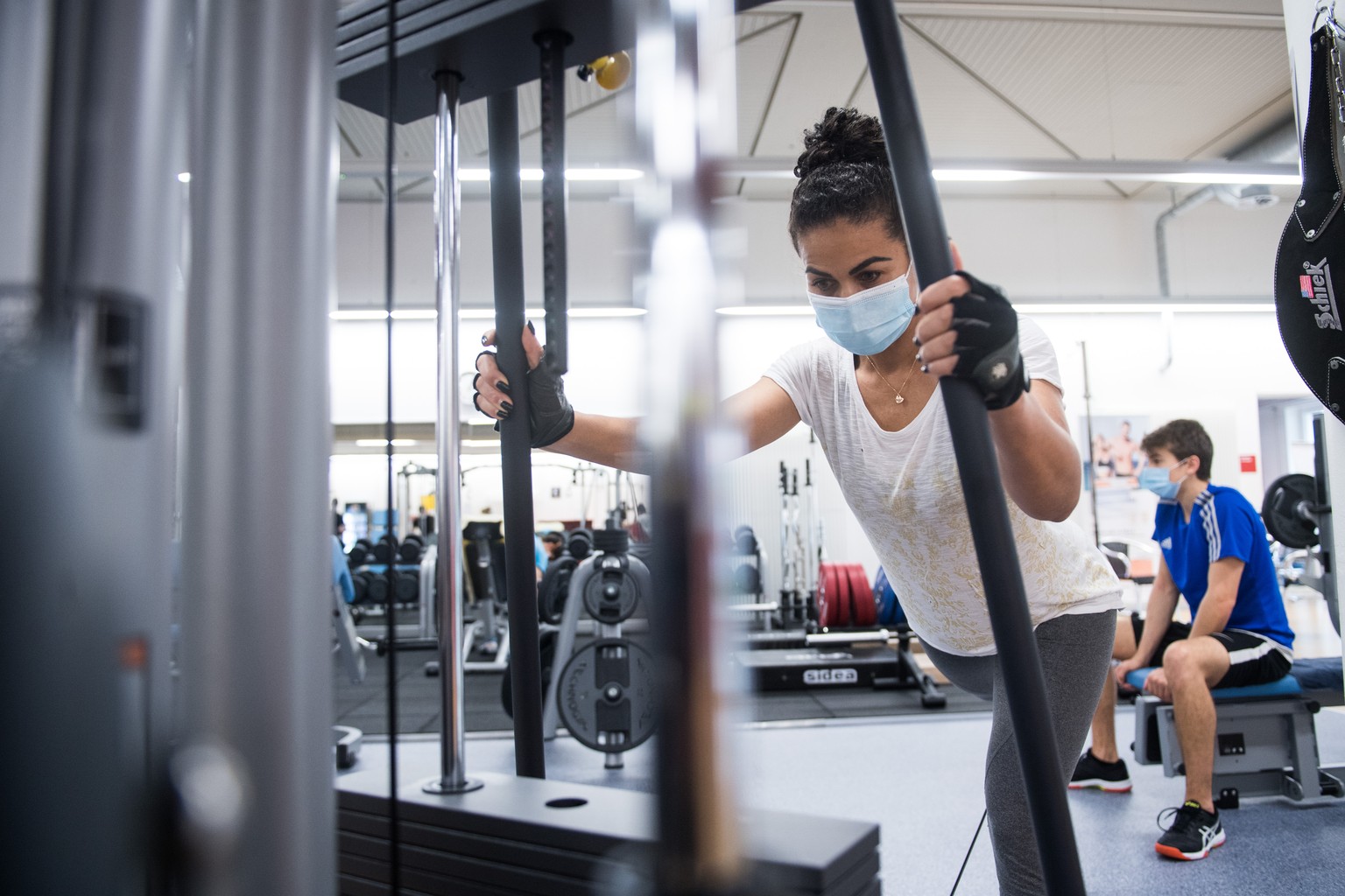 Eine Frau mit Hygienemaske trainiert an einem Kraftgeraet im Fitnessstudio Active Fitness in Bellinzona, am Dienstag, 3. Novermber 2020. In den Fitnesscentern ist das Tragen von Hygienemasken und die  ...