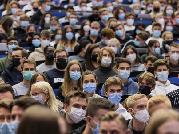 FILE - Students wear mouth-to-nose coverings while sitting close to each other during the lecture &quot;BWL 1&quot; in lecture hall H1 of the Westfaelische Wilhelms-Universitaet in Muenster, Germany,  ...