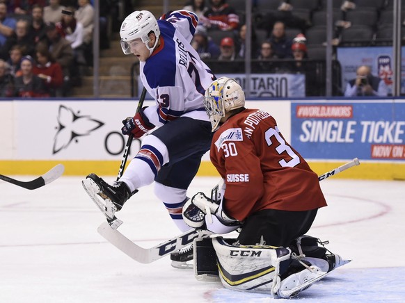 United States Kieffer Bellows (23) screens Switzerland goaltender Joren van Pottelberghe (30) during the first period of a quarterfinal hockey game at the world junior championship in Toronto, Monday, ...