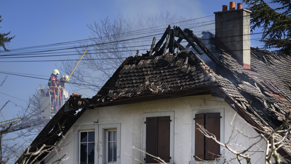 Firefighters watch from a ladder a villa where bodies were found after a fire, in Yverdon-les-bains, Switzerland, Thursday, March 9, 2023. An explosion followed by a fire took place Thursday morning i ...