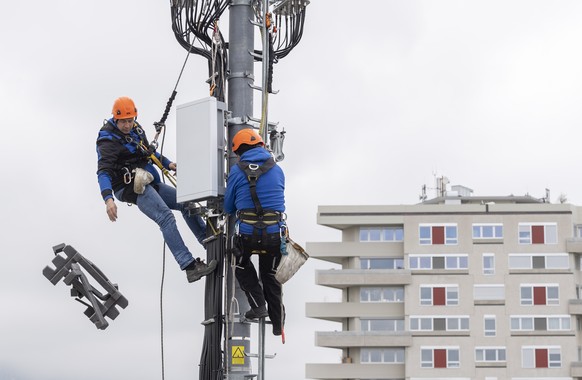 Deux employes de l&#039;entreprise Axians installent une antenne 5G de communication pour les mobiles sur un mat situe sur le toit d&#039;un immeuble du quartier de la Gradelle a Chene-Bougeries ce ve ...