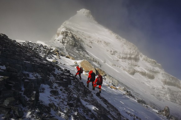 FILE - In this May 27, 2020, file photo released by Xinhua News Agency, members of a Chinese surveying team head for the summit of Mount Everest, also known locally as Mt. Qomolangma. China and Nepal  ...