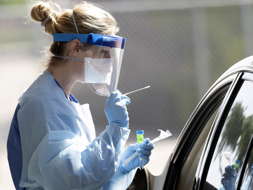 epa08388071 A health care worker with Stanford Health Valley Care takes checks a nasal swab sample from a person at a new drive-thru coronavirus COVID-19 testing center at the Alameda County Fairgroun ...