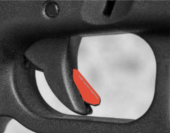 Externe Abzugssicherung bei einer Glock-Pistole. Am Abzugszüngel ist ein zusätzliche Lasche (rot markiert) angebracht, die ebenfalls mit dem Abzugsfinger gedrückt werden muss, damit ein Schuss abgegeb ...