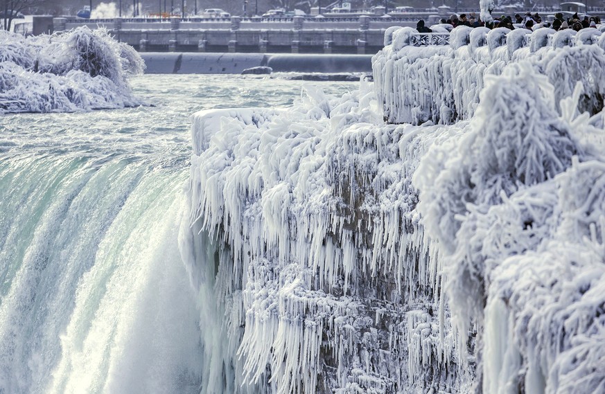 Visitors take photographs at the brink of the Horseshoe Falls in Niagara Falls, Ontario, as cold weather continues through much of the province on Friday, Dec. 29, 2017. (Aaron Lynett/The Canadian Pre ...