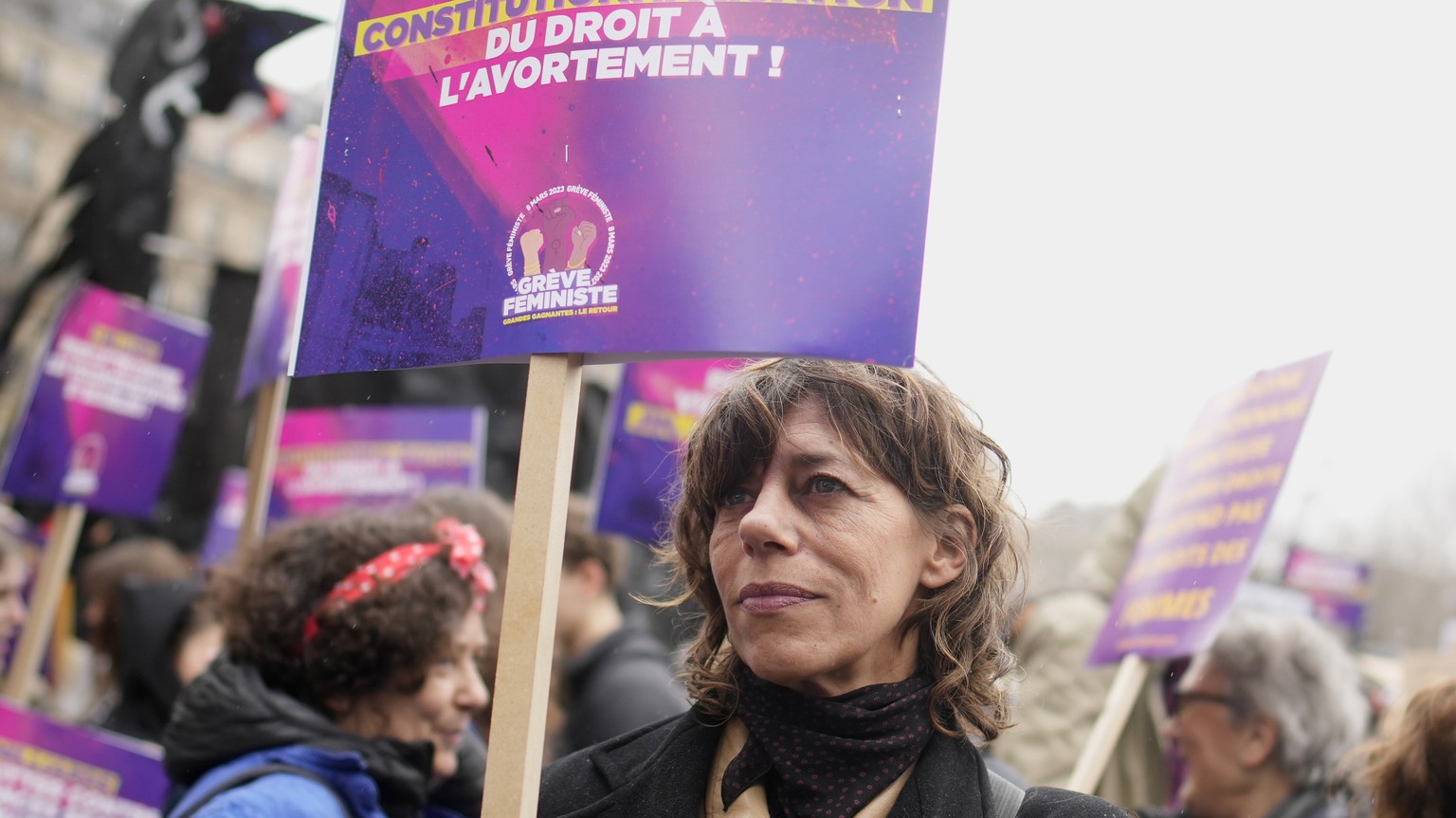 A woman demonstrates with a poster reading &quot;Abortion in the Constitution&quot; as part of the International Women&#039;s Day, Wednesday, March 8, 2023 in Paris. Feminist activists see the pension ...