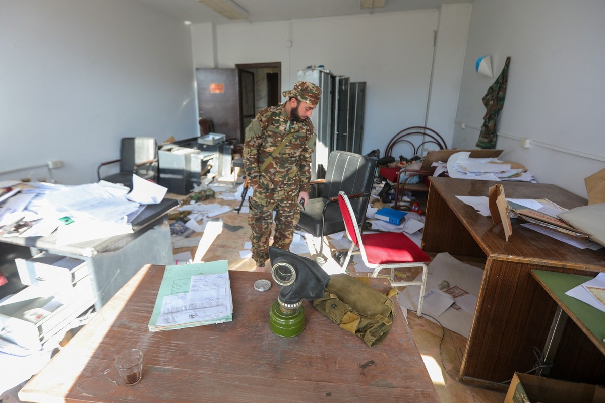 A member of the security forces of Syria's new authorities stands on a pile of papers in a room at the security bureau of the Fourth Division on the outskirts of Damascus on December 21, 2024. Ma ...