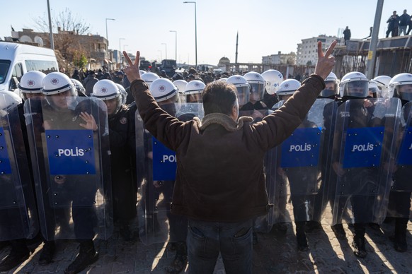 epa12665232 A pro-Kurdish protester faces Turkish police as they attempt to walk to the Kurdish-managed northeastern Syrian city of Qamishli during a demonstration in support of Syrian Kurds, in Nusay ...