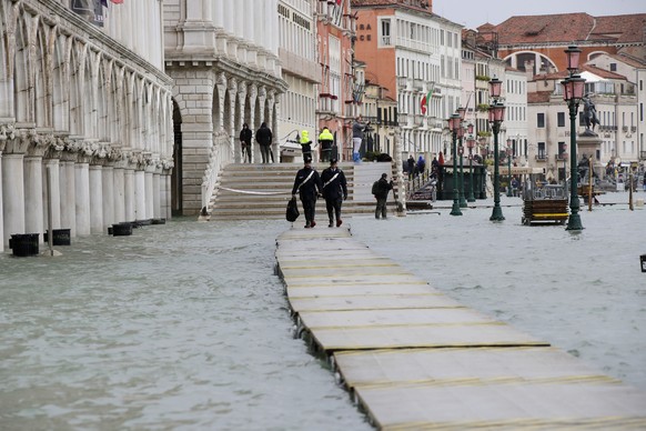 Two Carabinieri walk on a gangway in flooded Venice, Italy, Sunday, Nov. 17, 2019. Venetians are bracing for the prospect of another exceptional tide in a season that is setting new records. Officials ...