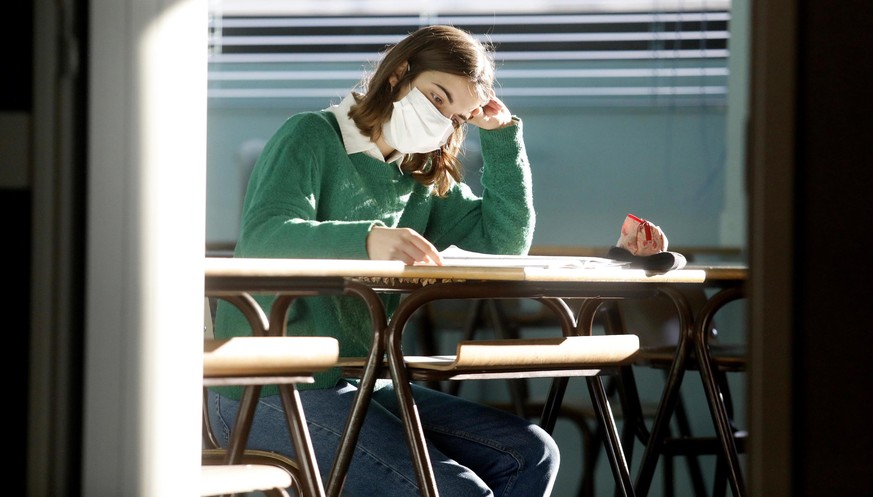 epa08963893 A student sits inside a classroom on the first day of reopening at the Volta High School in Milan, northern Italy, 25 January 2021, after a lockdown over the coronavirus disease (COVID-19) ...