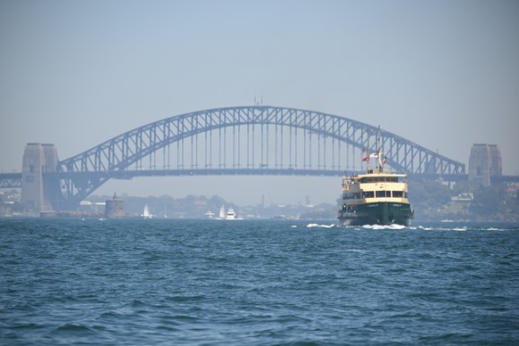 epa12579727 The Sydney Harbour Bridge is shrouded in heavy smoke haze as a Manly Ferry makes its way down the harbour during the 2025 SOLAS Big Boat Challenge, on Sydney Harbour in Sydney, Australia, ...