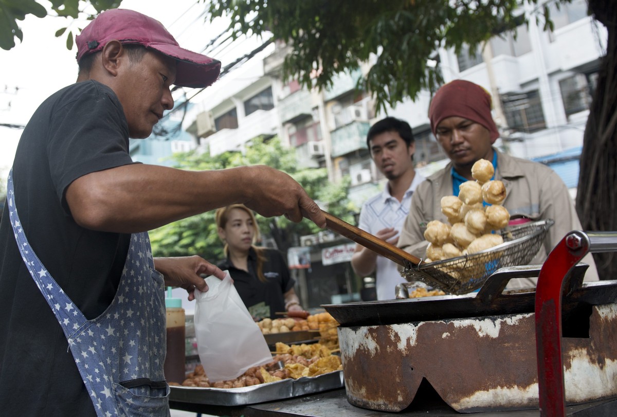 epa04912038 A Thai street vendor lifts deep fried fish balls out of a pot of oil on the side of a road in Bangkok, Thailand, 04 September 2015. Thailand's headline inflation on food prices in Aug ...