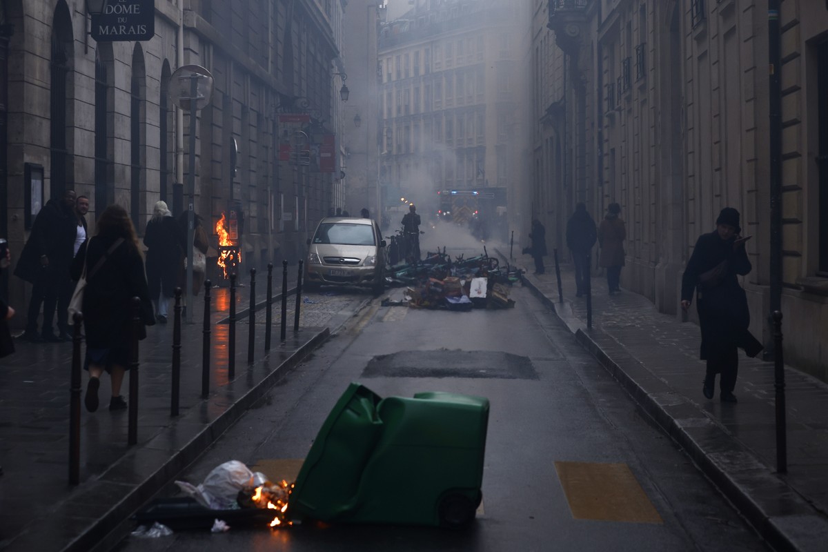 epaselect epa10572841 People walk past a fire during clashes at a rally near the Constitutional Council after the proclamation of the Council's decision about the government's pension reform ...