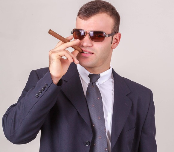 Höflicher erfolgreicher Geschäftsmann oder CEO mit Sonnenbrille, stehend im Anzug, eine große Zigarre rauchend MR:yes 081013RobertZDEU *** polite Successful Businessman Or CEO with Sunglasses, standin ...