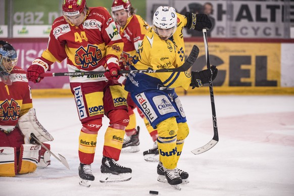 Davoser Marc Wieser, rechts, bringt Unruhe vors Tor von Biels Goalie Jonas Hiller, links, und Samuel Kreis im dritten Eishockey Playoff-Viertelfinalspiel der National League zwischen dem HC Biel und d ...