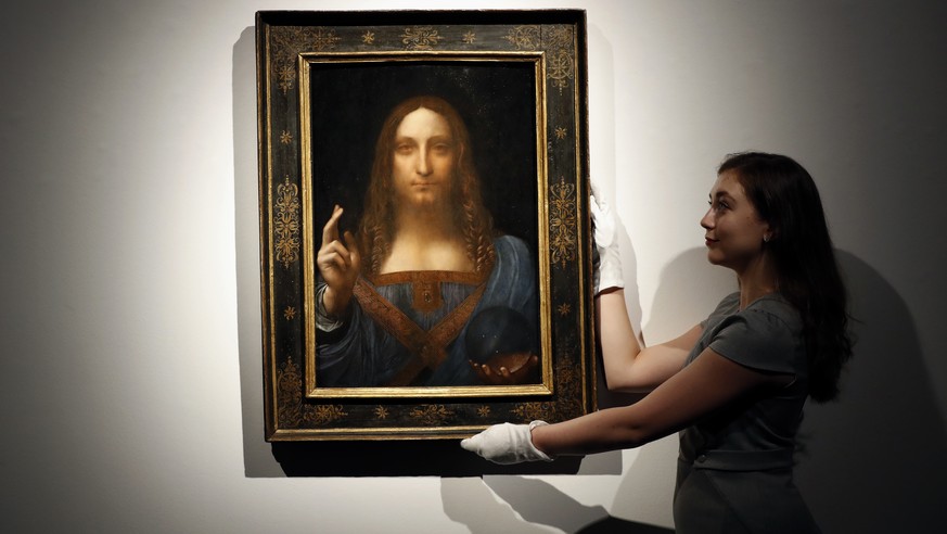 FILE - In this Oct. 24, 2017 file photo, an employee poses with Leonardo da Vinci&#039;s &quot;Salvator Mundi&quot; on display at Christie&#039;s auction rooms in London. Abu Dhabi’s Department of Cul ...