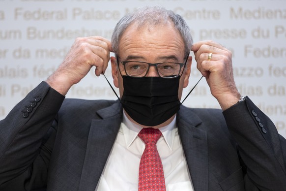 Bundespraesident Guy Parmelin zieht eine Maske an, waehrend einer Medienkonferenz des Bundesrates zur aktuellen Situation im Zusammenhang mit dem Coronavirus, am Dienstag, 30. November 2021, in Bern.  ...