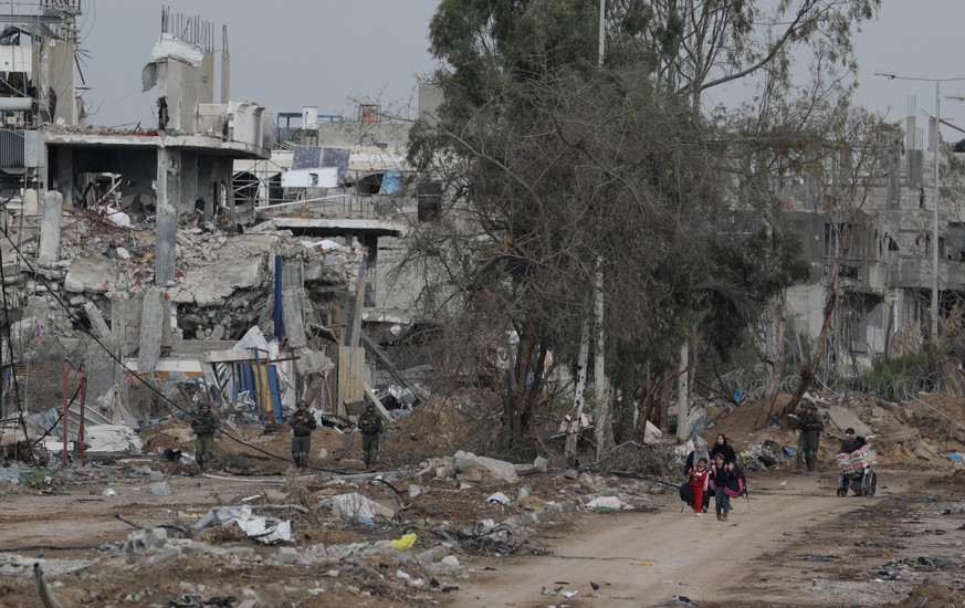 epa10999431 Palestinians walk after crossing from the northern Gaza Strip to the southern Gaza Strip as Israeli soldiers move along Salah Al Din road in the central Gaza Strip, 28 November 2023. After ...