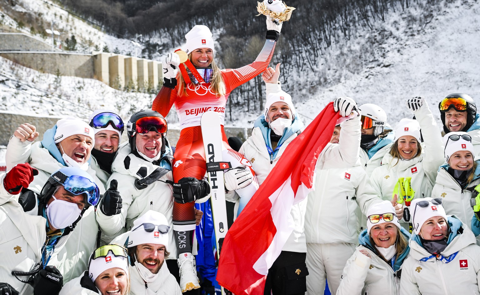 epa09757719 Gold medalist Corinne Suter of Switzerland celebrates with members of the Swiss team after the victory ceremony of the women&#039;s downhill race at the Beijing 2022 Olympic Games at the Y ...