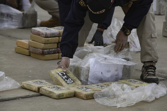 A police officer picks up a brick of cocaine during a presentation to the press of more than three tons of seized cocaine, at the police air base in Callao, Peru, Tuesday, October 8.  August 24, 2023. (AP Photo/G...