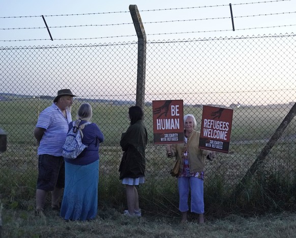 Protesters gather at the perimeter of Boscombe Down air force base in Amesbury, England on Tuesday June 14, 2022,, where an aircraft is believed to be the plane set to take asylum seekers from the UK  ...