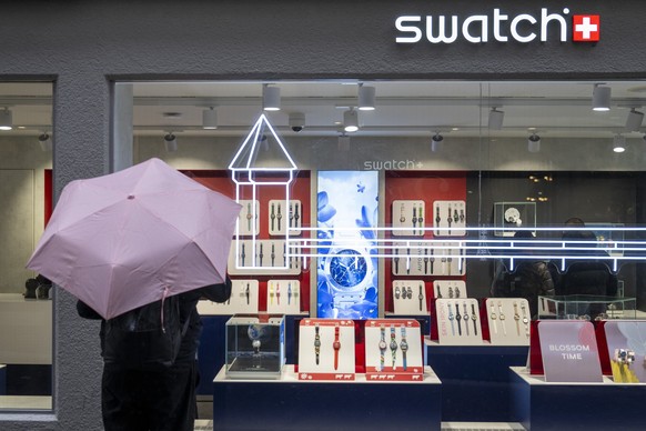 Passanten bei Regenwetter mit Regenschirmen besichtigen ein Schaufenster eines Uhrengeschaefts an der Grendelstrasse in der Altstadt von Luzern am Mittwoch, 16. April 2025. (KEYSTONE/Urs Flueeler).