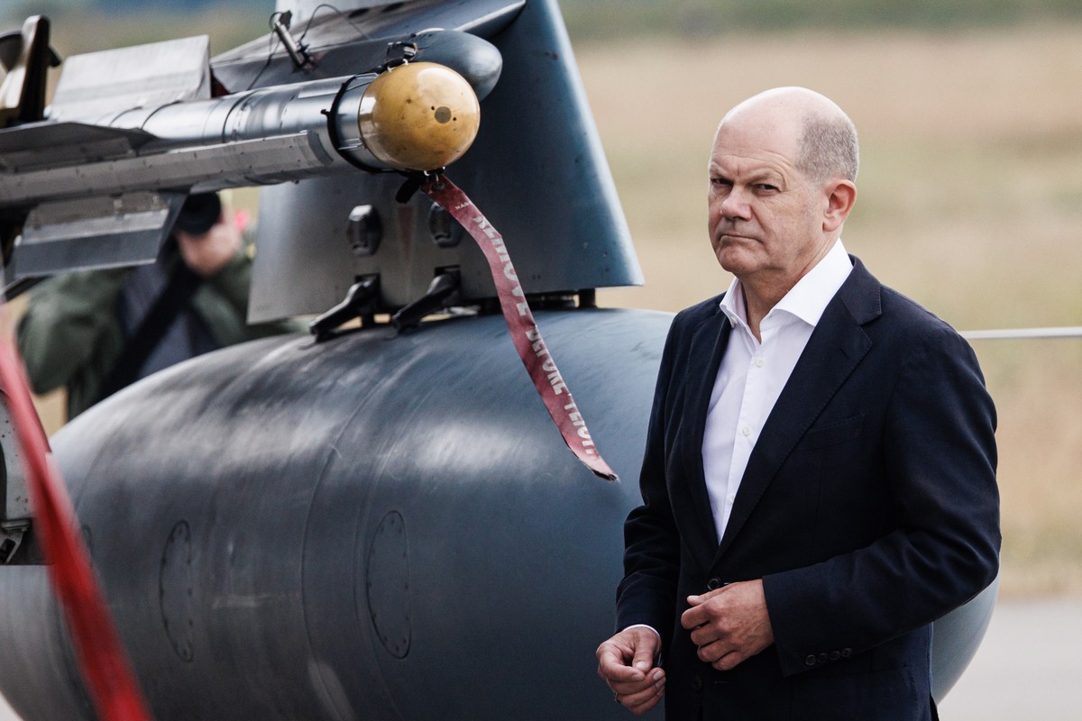 epa10694861 German Chancellor Olaf Scholz walks next to a 'Tornado' fighter jet with an IRIS-T medium range infrared homing air-to-air missile installed during his visit of the NATO Air Defe ...