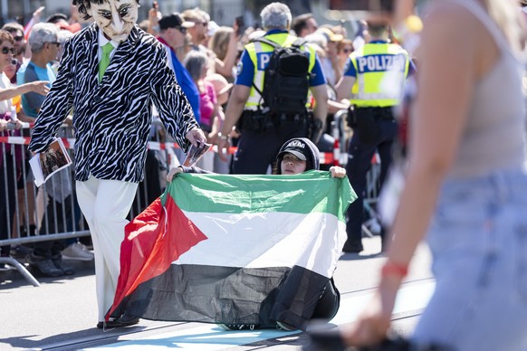 A demonstrator sits on the street with a palestine flag during the opening ceremony of the 69th Eurovision Song Contest in Basel, Switzerland, on Sunday, May 11, 2025. (KEYSTONE/Til Buergy)