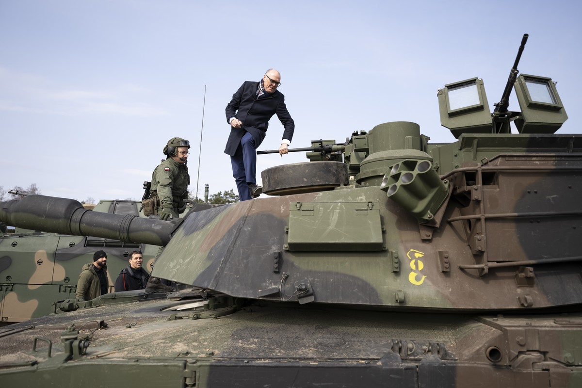 Swiss Federal Councillor and Minister of Defence Martin Pfister, right, climbs on a Polish army tank next to a Polish soldier, during a visit to the Wesola military base in Warsaw, Poland, Friday, Mar ...