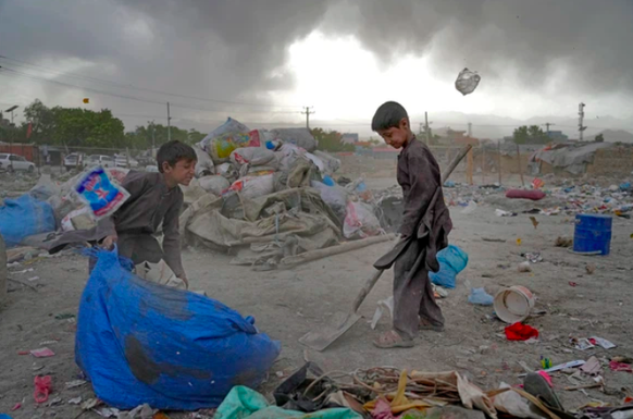 Zwei afghanische Kinder sammeln wiederverwertbares Material von einer Müllhalde.