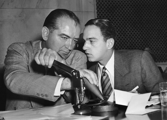 Sen. Joseph McCarthy covers the microphones with his hands while having a whispered discussion with his chief counsel, Roy Cohn, during a committee hearing in Washington in this April 26, 1954 photo.  ...