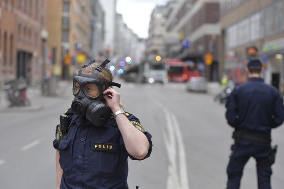 epa05894613 A Swedish police officer adjusts her gas mask as they guard the area after a truck reportedly crashed into a department store in central Stockholm, Sweden, 07 April 2017. A truck has drive ...