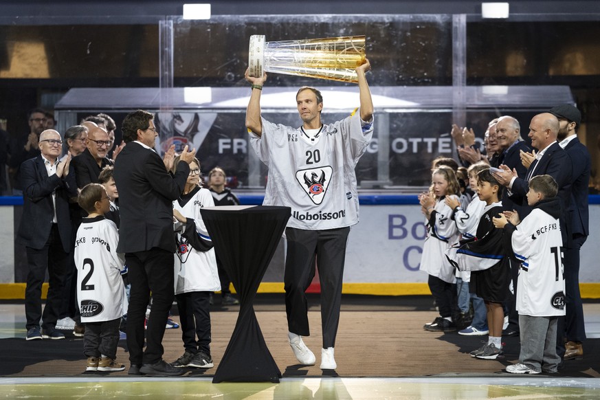 Der ehemalige Kapitaen des HC Fribourg-Gotteron Julien Sprunger hebt den Pokal hoch neben die ehemaligen Kapitaene des HC Fribourg Gotteron, links, und die ehemaligen Praesidenten des HC Fribourg Gott ...