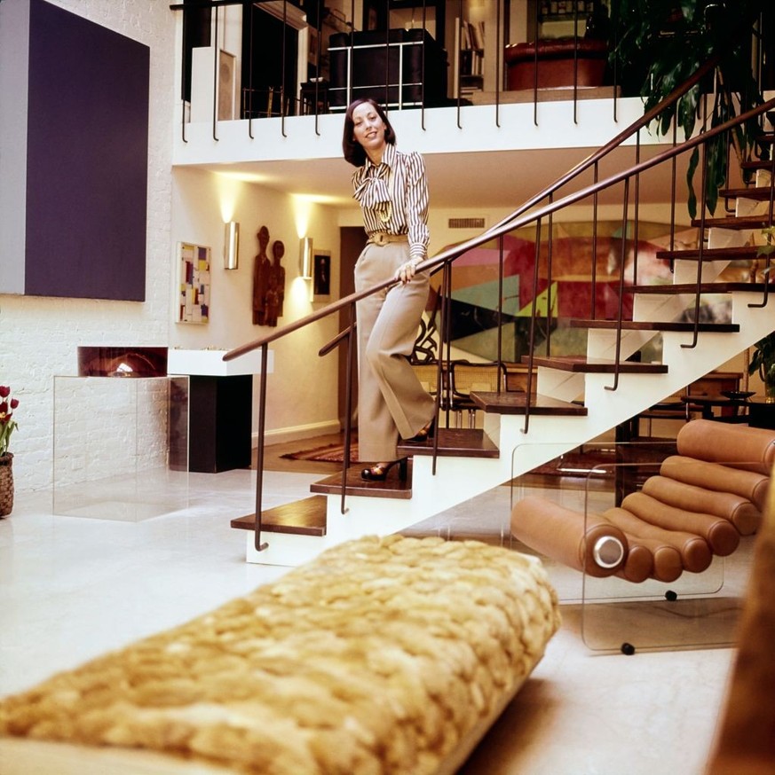 Vogue, June 01, 1973 - Art collector and chairman of the junior Council of the Museum of Modern Art, Barbara Jakobson, descending her spiral staircase. In the foreground is a fur covered bench, painti ...