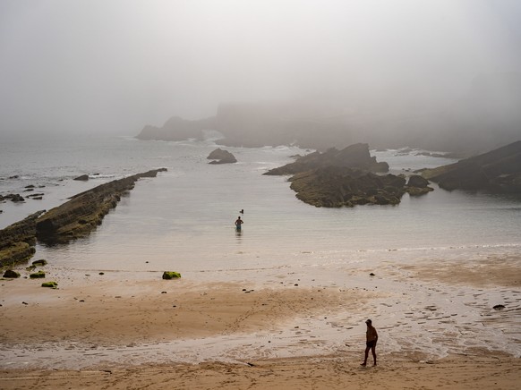 epa10014141 Two people enjoy the beach in Santander, Spain, 15 June 2022. The early and powerful heatwave in Spain reach its peak , with 44 degrees in the Guadalquivir valley, 42 degrees in the Tagus  ...