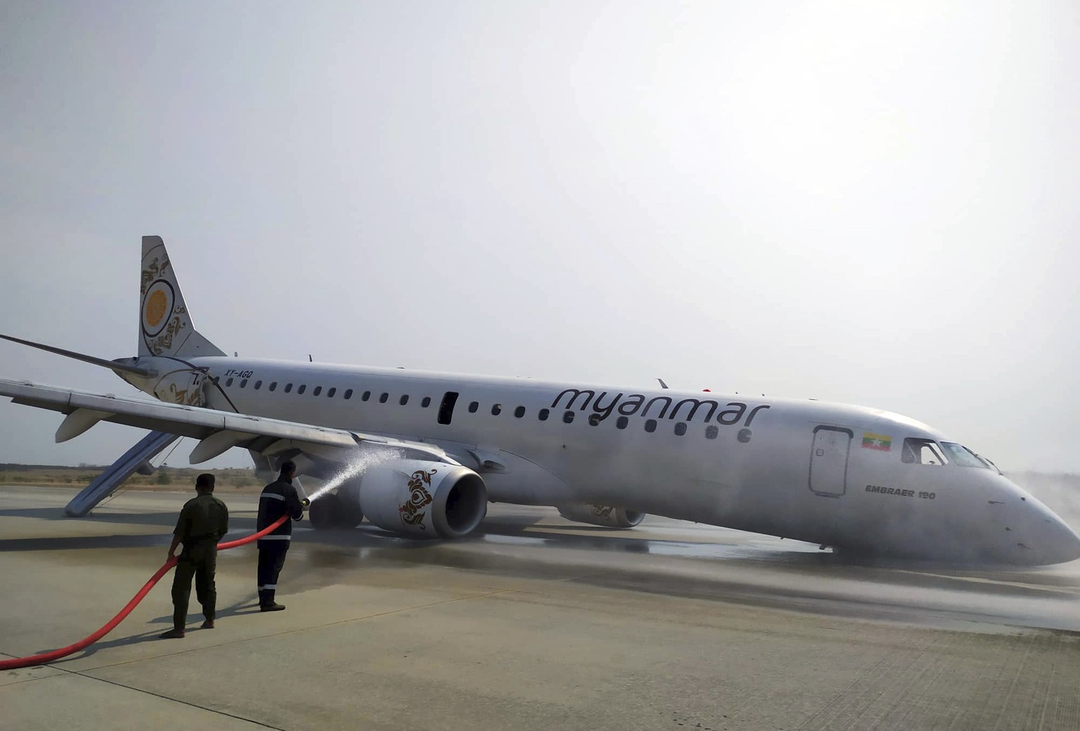 Firefighters work with hose on a plane of Myanmar National Airline (MNA) after an accident at Mandalay International airport Sunday, May 12, 2019, in Mandalay, Myanmar. All passengers and crew are rep ...