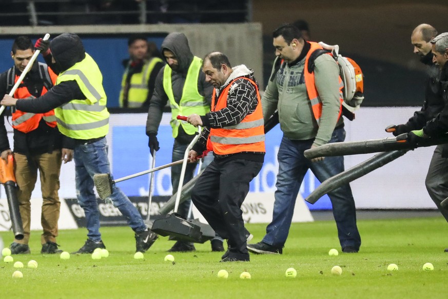 epa06544056 Workers clean the field of tennis balls thrown onto the field as a sign of protest during the German Bundesliga soccer match between Eintracht Frankfurt and RB Leipzig in Frankfurt Main, G ...