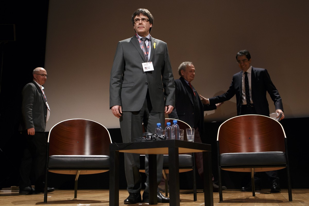 Catalan leader Carles Puigdemont, 2nd left, attends a panel titled "Self-determination", past Nicolas Levrat,Êleft, Director of Department International Public Law and International Organisa ...
